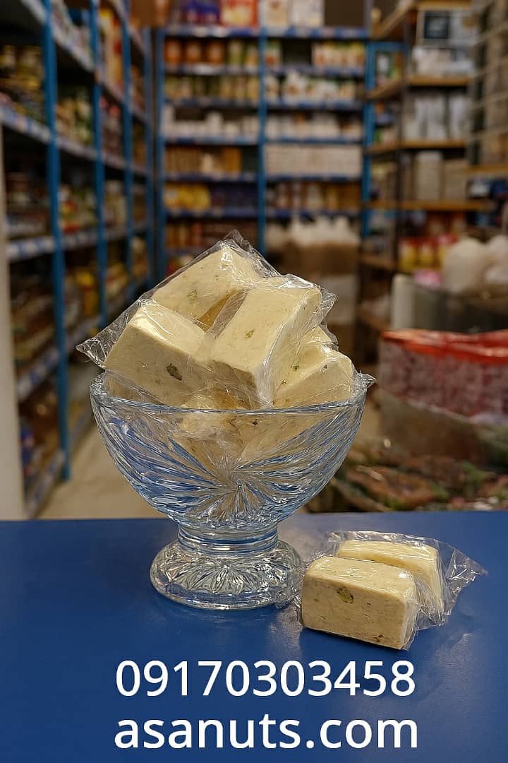 ظرف کریستالی حاوی گز با بسته‌بندی شفاف روی پیشخوان آبی سوپرمارکت، همراه با شماره تماس و آدرس سایت.